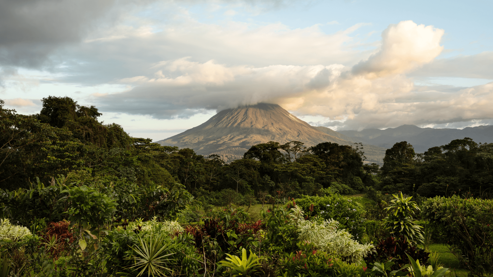 Vue sur le volcan Arenal au Costa Rica, entouré de jungle verdoyante et coiffé de nuages épais